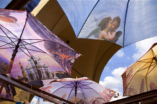 ITALY, Tuscany, Florence, Brightly coloured umbrellas for sale on the Ponte Vecchio with images of Florence and cherubs on them