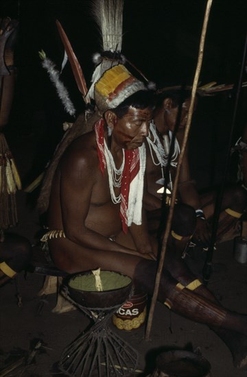 COLOMBIA, North West Amazon, Tukano Indigenous People, "Barasana shamans and elders led by revered shaman Cristo chant to reach ancient world of ancestors, holding sacred hardwood prayer staves some wearing ancient quartz pendants wild boar teeth belts and traded white glass beads. Refined coca powder handed round by gourd and taken from deer bone spoon"