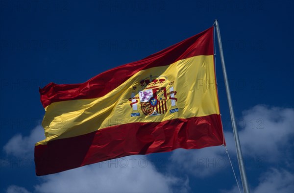 SPAIN, Pais Valenciano, Costa Blanca, Alicante.  Spanish flag flying against blue sky and white clouds.