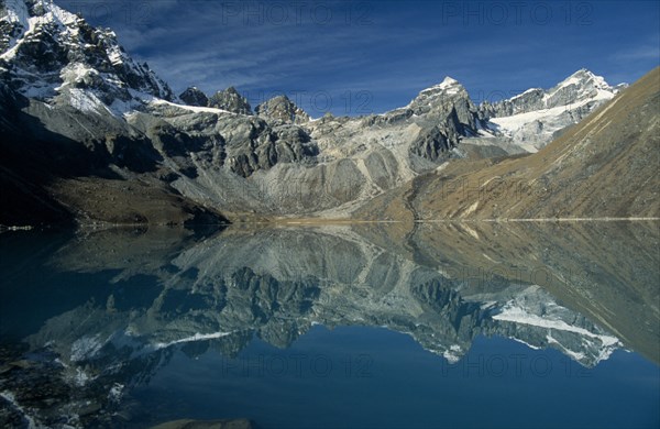 NEPAL, Everest Trek, Gokyo, View west over Dudh Pokhari Lake with snow capped mountains reflected in the water