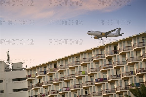 SPAIN, Balaeric Islands, Ibiza, Eivissa. Charter flight coming into land at Ibiza airport (Aeroport d'Eivissa) with tourist hotel in the foreground. Jon Hicks.