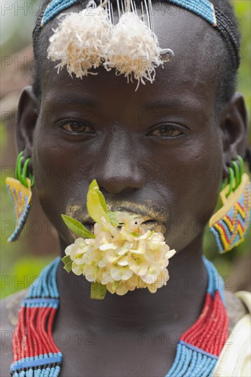 ETHIOPIA, Lower Omo Valley, "Key Afir,", Tsemay man with flower in mouth at weekly marke