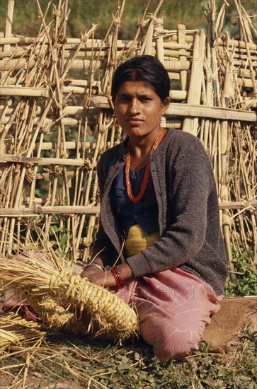 NEPAL, East, Near Chainpur, Portrait of woman with a nose piercing sat on the ground weaving in Mayam Village