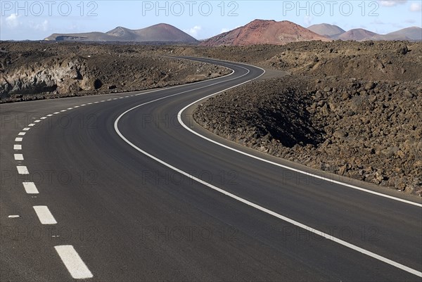 SPAIN, Canary  Islands, Lanzarote, Distant view of Timanfaya National Park and the Montanas del Fuego from scenic west coast road following bend in foreground.