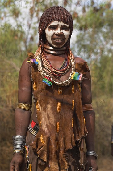 ETHIOPIA, Omo Valley, Mago National Park, "Woman with face painting, her hair greased with ocher colouring and animal fat into plaits known as Goscha and traditional goatskin dress decorated with cowrie shells "