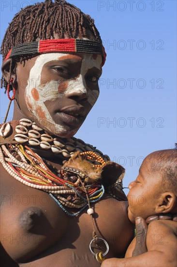 ETHIOPIA, Lower Omo Valley, Mago National Park, "Karo woman with face painting, breast feeding baby."