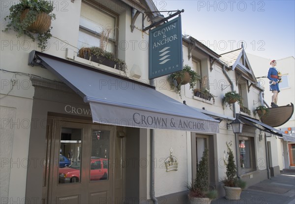 ENGLAND, West Sussex, Shoreham-by-Sea, Exterior of the Crown and Anchor public house in the high street with large ships mast head figure on the front of the building.