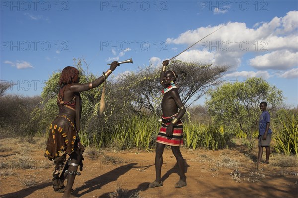 ETHIOPIA, Lower Omo Valley, Tumi, "Hama Jumping of the Bulls initiation ceremony. Man whipping women on back in ritual flogging