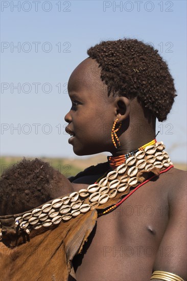 ETHIOPIA, Lower Omo Valley, Tumi, Dombo village (Hamer peoples) Hamer lady with baby in goatskin sling decorated in cowrie shells Jane Sweeney