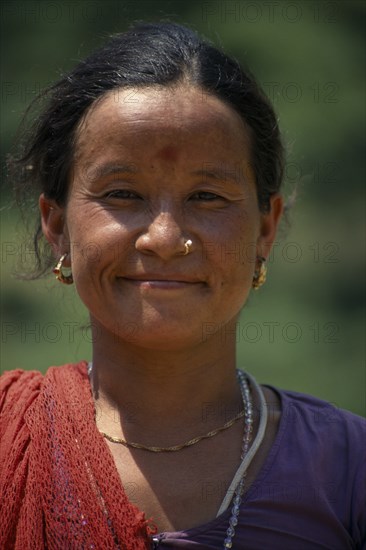 NEPAL, Dhorpatan Trek, Near Tatopani, Head and shoulders portrait of woman wearing nose ring smiling in Baloti Village