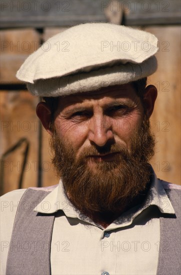 PAKISTAN, North West Frontier, Chitral, Head and shoulders portrait of a man with a beard wearing a hat in the bazaar in Chitral