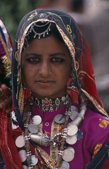 INDIA, Rajasthan, Bikaner, Portrait of a young tribal woman wearing traditional dress and jewellery before the start of the Camel Festival