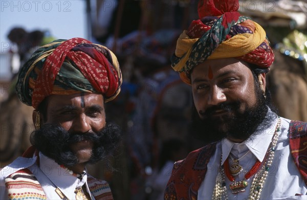 INDIA, Rajasthan, Bikaner, Two Rajput men with beards wearing ceremonial dress and turbans at the start of the Camel Festival