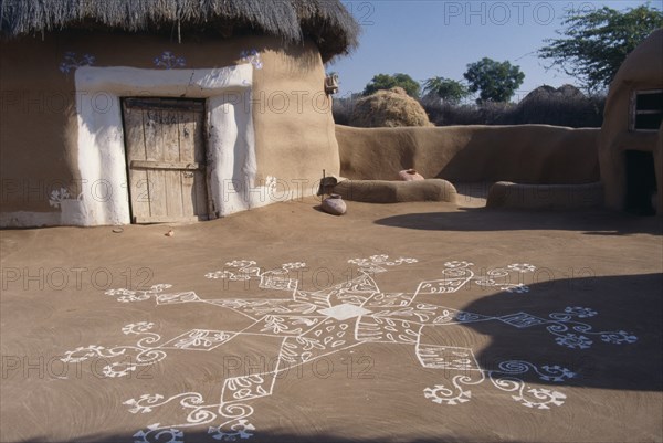 INDIA, Rajasthan, Katariasar, Village hut decorated for the Camel Festival with white painted motifs on the ground outside