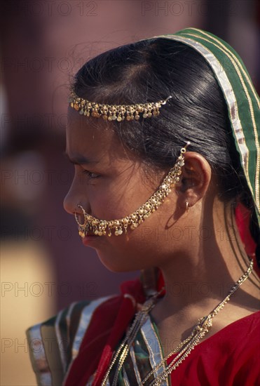 INDIA, Rajasthan, Jhunjhunu, Portrait side profile of a girl wearing traditional dress and jewellery before the start of the Shekhawati Festival