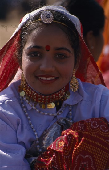 INDIA, Rajasthan, Jhunjhunu, Portrait of a young girl dancer smiling wearing traditional dress and jewellery before the start of the Shekhawati Festival