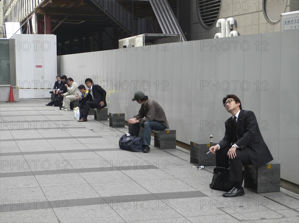 JAPAN, Honshu, Tokyo, "Tokyo Station, Nihonbashi entrance, morning commuters take a break outside before going to work, some smoke cigarette"