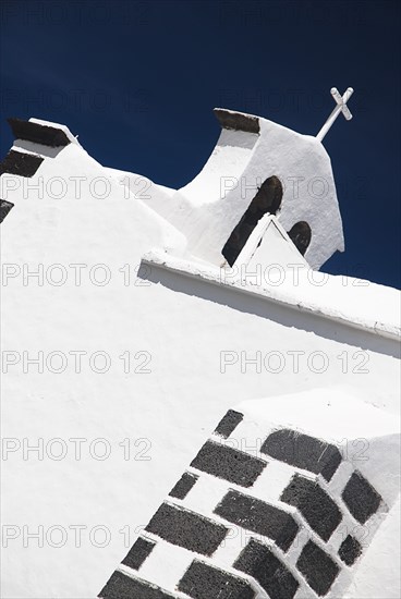 SPAIN, Canary  Islands, Lanzarote, "Mancha Blanca village.  Ermita de los Dolores or Hermitage of the Sorrows, angled detail of white painted church roof and bell tower."