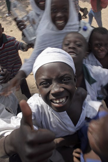 GAMBIA, Western Gambia, Tanji, "Tanji Village.  Happy, laughing children wanting to be photographed and trying to get the best position while having a break from lessons at the Ousman Bun Afan Islamic school.  Child in centre foreground making a thumbs up gesture. "