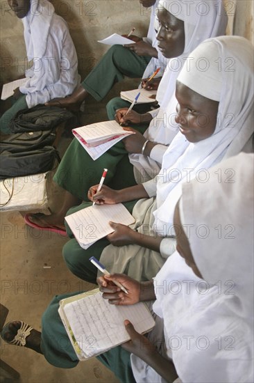 GAMBIA, Western Gambia, Tanji, "Tanji Village.  African Muslim girls wearing white headscarves while attending a class at the Ousman Bun Afan Islamic school, sitting in line writing in exercise books."