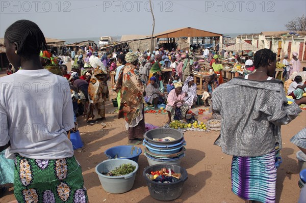GAMBIA, Western Gambia, Tanji, Busy market scene with women selling fruit and vegetables and coloufully dressed crowd.
