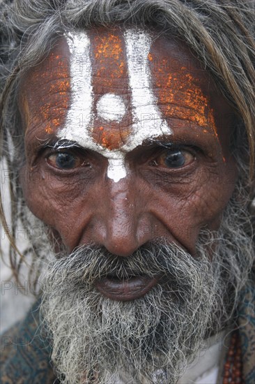INDIA, Rajasthan, Udaipur, "Portrait of elderly male Hindu beggar outside the Jagdish Temple.  With painted forehead, grey beard and fixed stare."