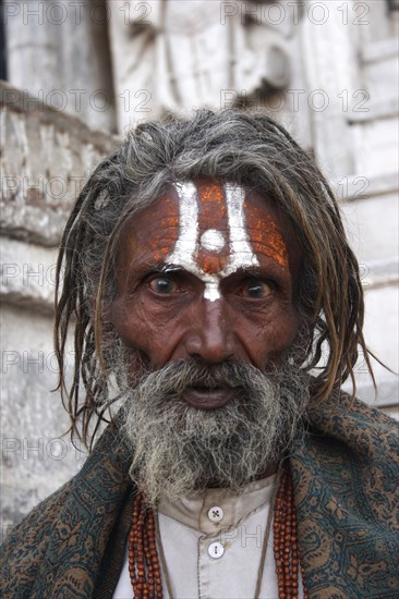 INDIA, Rajasthan, Udaipur, "Head and shoulders portrait of elderly male Hindu beggar in front of the Jagdish temple with painted forehead and wide eyed, fixed stare."