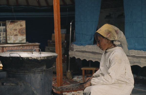 MONGOLIA, People, Khalkha winter sheep camp. Shepherd's wife cooking traditional meat dumplings over normal iron stove inside ger yurt for Tsagaan Tsaar Lunar New Year's celebrations