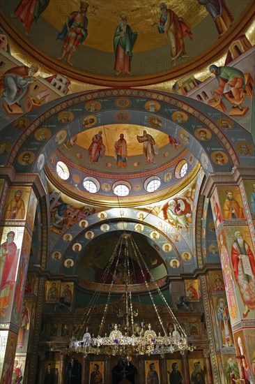 ISRAEL, Hazafon, Sea of Galilee, "Nazareth.  Interior of the Greek Orthodox Church of St. Gabriel also known as the Church of the Annunciation, located over the spring that fed Marys Well.  Interior domed ceilings and archways decorated with paintings of biblical scenes and the saints, wall hangings and tiled mosaics.  Ornate candelabra hanging from centre framed by arch."