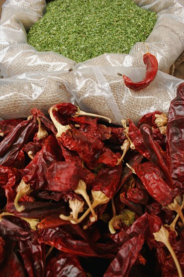 ISRAEL, Jerusalem, "Jerusalem food market.  Open sacks of dried, red, hot chili peppers and green herbs.  Close cropped view filling frame."