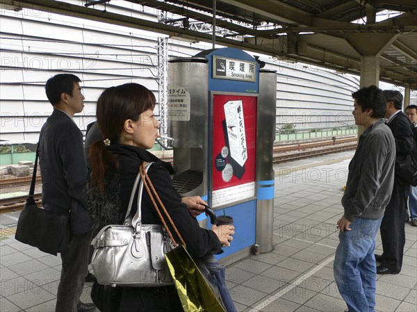 JAPAN, Honshu, Tokyo, "Yurakucho - the smokers spot on the train platform, men and a young woman smoking"
