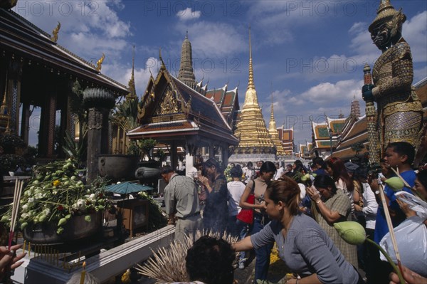 THAILAND, Bangkok, Crowds making offerings of incense and lotus flower buds at shrine in the Royal Palace during Lotus Flower Festival.