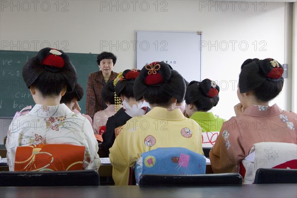 JAPAN, Honshu, Kyoto, "Gion area, the neighbourhood where Geisha live, study and perform.  Maiko apprentice Geisha attending a class at Mia Garatso school of Geisha, seated with backs to camera looking towards female teacher."