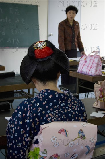 JAPAN, Honshu, Kyoto, "Gion District, the neighbourhood where Geisha live, study and perform.  Geisha, wearing a kimono and obi attending an English class and talking to the teacher at Mia Garatso school for Geisha and maiko apprentice Geisha."