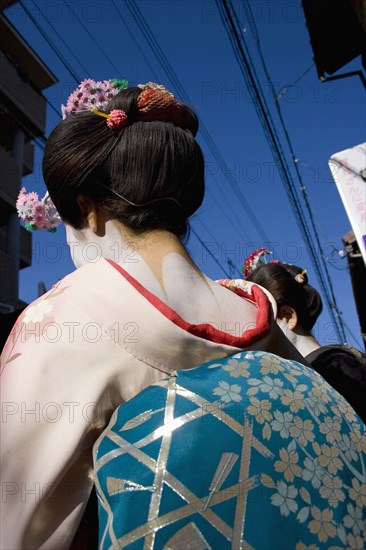 JAPAN, Honshu, Kyoto, Gion District.  Back of Geisha wearing pale pink silk kimono with turquoise and silver obi.  Hair is worn up and fixed with decorative pins and flowers exposing the unpainted nape of the neck which is considered sensuous.