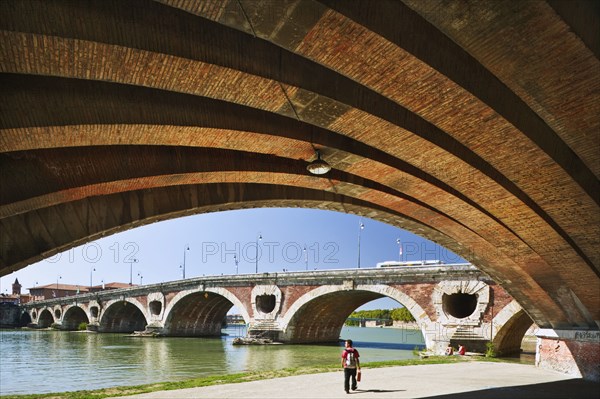 20091063 Pont Neuf  red brick bridge over river Garonne. French One individual Solo Lone Solitary Western Europe  Dominant RedDominant BlueArchitectureUrbanTransportWaterPeople - Single Person Jon Hicks 20091063 FRANCE Midi Pyrenees Toulouse