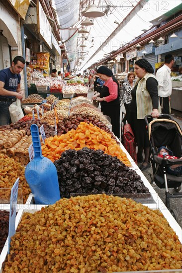 ISRAEL, Jerusalem, "Women with baby in pram making purchase at stall selling dried fruit and nuts including sultanas, apricots and peanuts in covered main food market of Jerusalem"