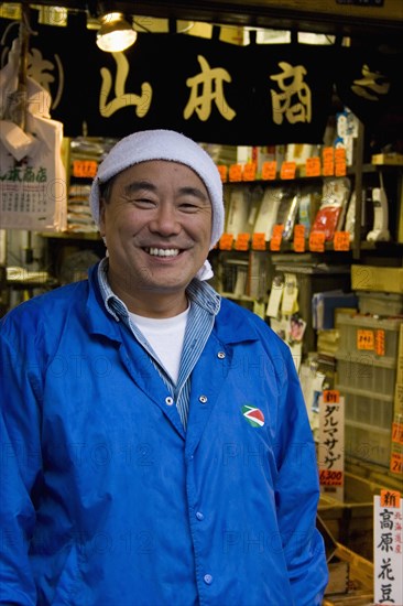 JAPAN, Honshu, Tokyo, Tsukiji fish market.  Three-quarter portrait of smiling Japanese man selling herbs at the worlds biggest fish and food market the known as ‘the stomach of Tokyo.