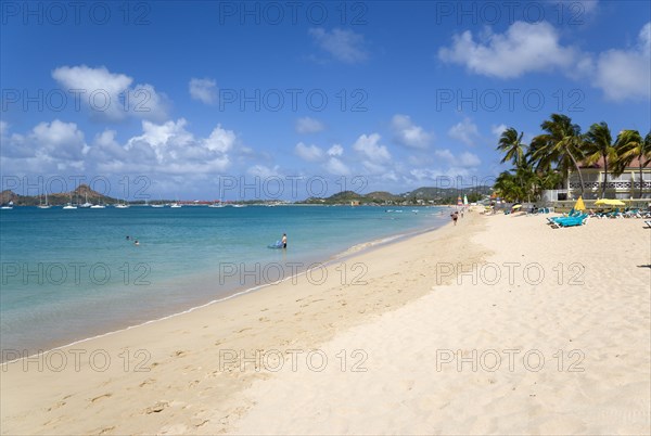 WEST INDIES, St Lucia, Gros Islet, Reduit Beach in Rodney Bay with tourists in the water and on the beach with yachts at anchor in the bay