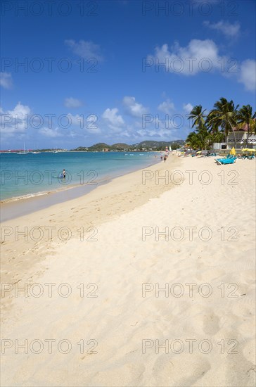WEST INDIES, St Lucia, Gros Islet, Reduit Beach in Rodney Bay with tourists in the water and on the beach with yachts at anchor in the bay