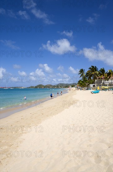 WEST INDIES, St Lucia, Gros Islet, Reduit Beach in Rodney Bay with tourists in the water and on the beach with yachts at anchor in the bay