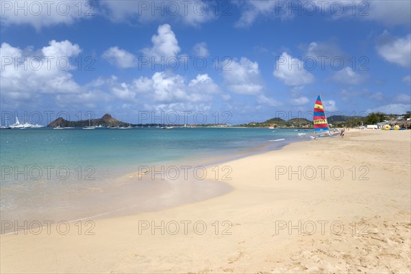WEST INDIES, St Lucia, Gros Islet, Reduit Beach in Rodney Bay with tourists in the water and on the beach with yachts at anchor in the bay