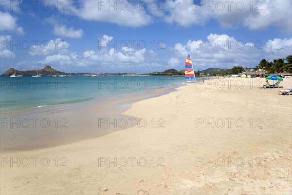 WEST INDIES, St Lucia, Gros Islet, Reduit Beach in Rodney Bay with tourists in the water and on the beach with yachts at anchor in the bay