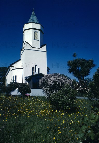 IRELAND, County Kerry, Sneem, Exterior of white church building with wild flowers and flowering shrubs in the foreground.