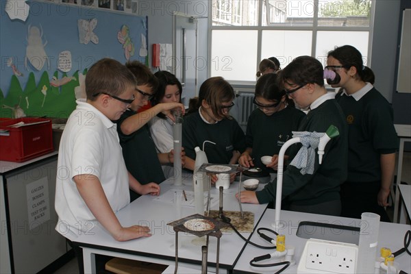 CHILDREN, Education, Secondary, Food technology science pupils carrying out an experiment to measure the evaporation of a salt solution using a bunsen burner.