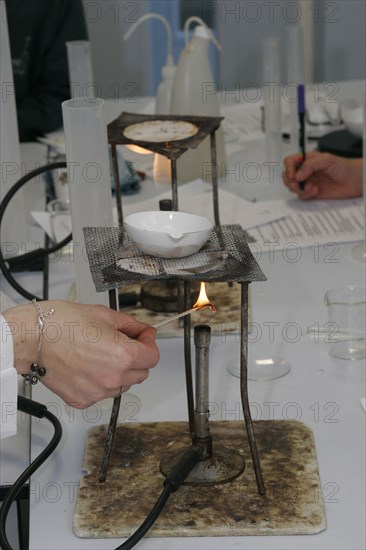 CHILDREN, Education, Secondary, Teacher lighting a bunsen burner prior to it being used for a food technology experiment measuring the evaporation of a salt solution.