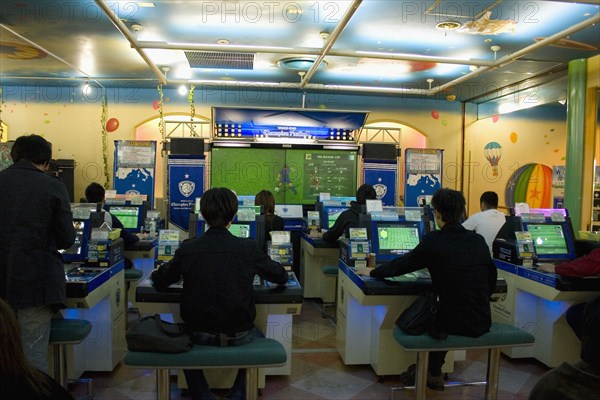 JAPAN, Honshu, Tokyo, Shinjuku. Young Japanese seated in front of computer screens soccer video game.