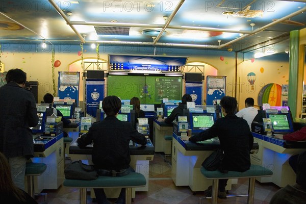 JAPAN, Honshu, Tokyo, Shinjuku.  Young Japanese seated in front of computer screens soccer video game.