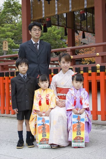 JAPAN, Honshu, Kyoto, "Fushimi-Inari Taisha, Fushimi-Ku Fukakusa Yabunouchi-cho.  Japanese family wearing formal suits and traditional kimonos posing for photographs at the entrance of the Fushimi-Inari Taisha shrine dedicated to Inari the deity of rice and sake and believed to bring prosperity."