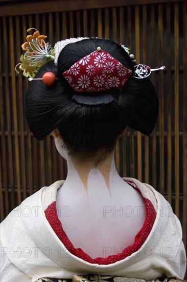JAPAN, Honshu, Kyoto, "Gion District.  Head and shoulders of Geisha, photographed with back to camera showing neck and shoulders painted white except for part of accentuated nape, left unpainted and considered sensuous.  Hair worn up with decorative pins and wearing  traditional kimono"